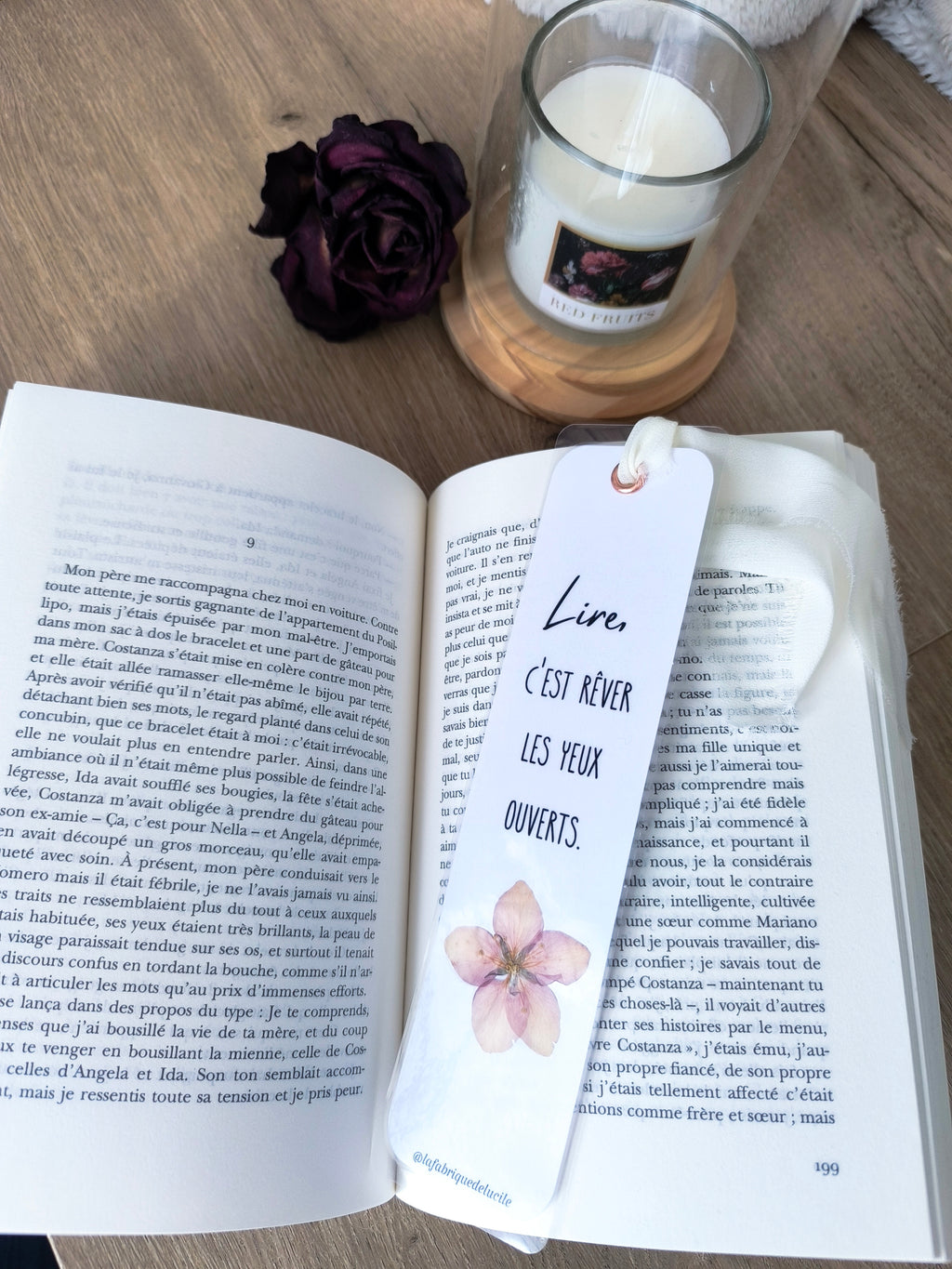 Marque-page floral avec citation 'Lire, c'est rêver les yeux ouverts', rose séchée et bougie sur bois